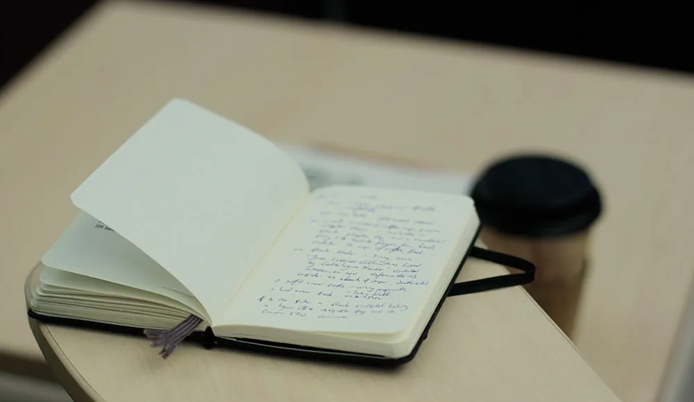 Notebook open on a desk with coffee